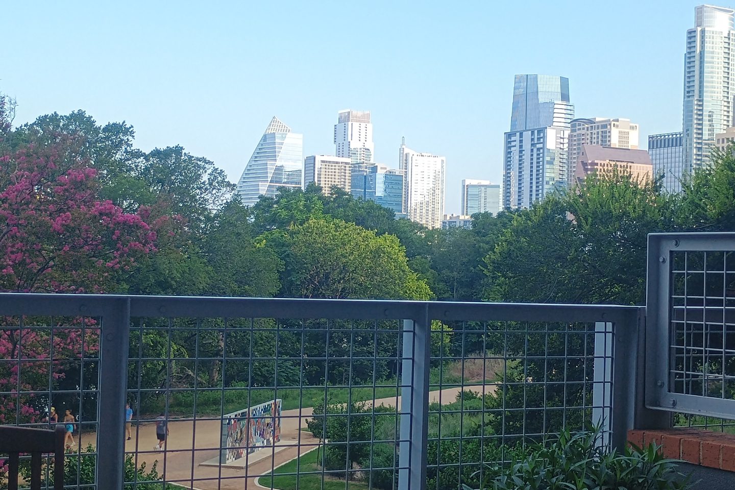 Downtown Austin skyline above the trees and a park trail, seen from the Floorpop LLC office on Rainey Street
